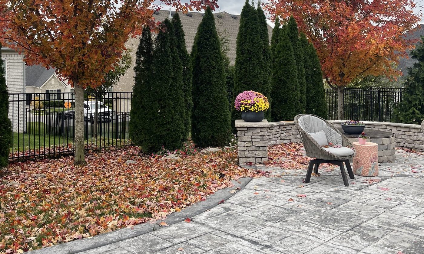 Stone patio surrounded by autumn trees and potted mums — where Sukha Sundays takes place